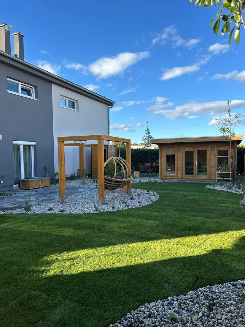 Dřevěná pergola a zahradní domek na okraji trávníku